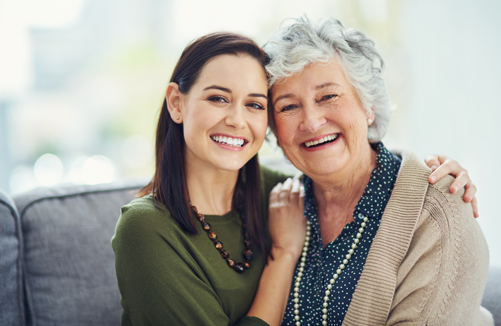A young woman hugging an older woman, both smiling.
