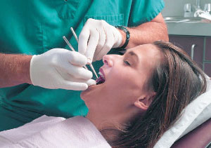 A woman relaxes in a dental chair without any display of anxiety while the dentist provides care.