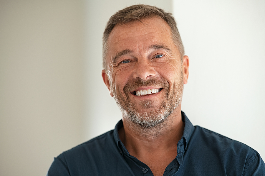 A middle-aged man smiles confidently.